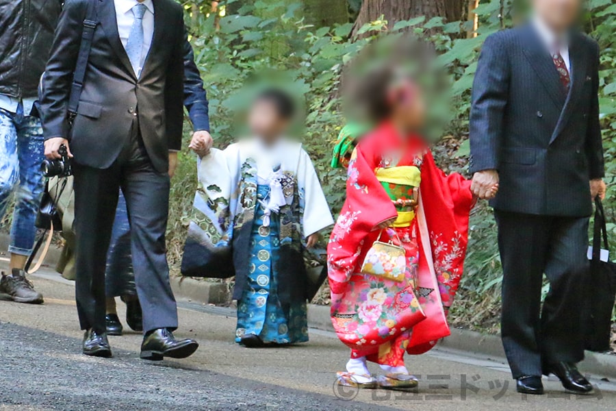 神社本殿前でかわいい表情で記念撮影する七五三三歳ちゃんの様子